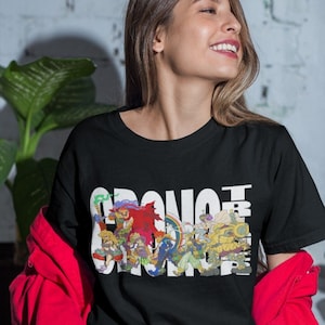 May include: A black t-shirt with a white graphic print of a group of cartoon characters. The characters are arranged to spell out the word "CHRONICLES".