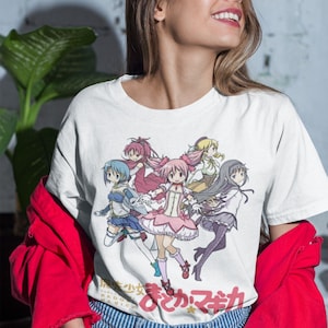 May include: White t-shirt with a colorful anime graphic of five girls in various poses. The text "魔法少女まどか☆マギカ" is printed on the bottom of the shirt.
