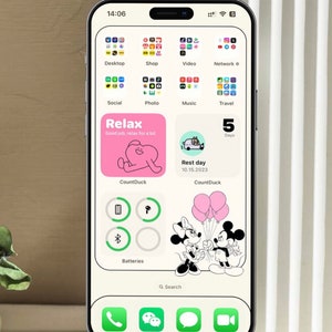 K&ouml;nnte beinhalten: Ein Smartphone-Bildschirm, der einen angepassten Startbildschirm mit einem rosa-wei&szlig;en "Relax"-Widget, einem wei&szlig;en Widget mit einem Cartoon-Auto und dem Text "Ruhetag 10.15.2023", einem gr&uuml;nen Widget mit einem Bluetooth-Symbol, einem wei&szlig;en Widget mit einem Batteriesymbol und einem Schwarzwei&szlig;-Cartoon-Bild von Mickey Mouse und Minnie Mouse, die Ballons halten, anzeigt.