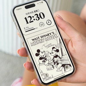 K&ouml;nnte beinhalten: Eine transparente Handyh&uuml;lle mit einer Schwarzwei&szlig;illustration von Mickey Mouse und Minnie Mouse aus einem Walt Disney Comic. Die Handyh&uuml;lle hat einen schwarzen Rand und eine transparente R&uuml;ckseite. Die Handyh&uuml;lle befindet sich auf einem Handy mit einem schwarzen Bildschirm, auf dem die Uhrzeit 12:30 und das Datum 10/10 angezeigt werden. Das Handy wird von einer Hand gehalten.