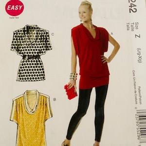 May include: Sewing pattern with illustrations of three different tops. One is a red cowl neck tunic, another is a black and white polka dot top with a belt, and the third is a yellow top with a cowl neck. The word "EASY" is in a red circle.