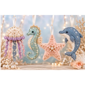 Peut inclure: Quatre décorations en feutrine suspendues par des rubans, représentant une méduse crème et lavande, un hippocampe bleu clair, une étoile de mer rose pâle et un dauphin bleu. Chaque créature marine est ornée de broderies blanches et de paillettes.