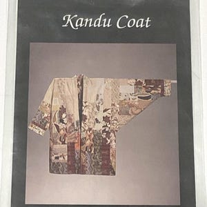 May include: A patchwork coat with the text "Kandu Coat" at the top. The coat is made of various fabric patterns in shades of beige, brown, and burgundy. The coat is displayed on a gray background.