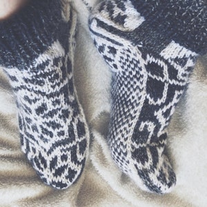 May include: A pair of cosy, black and white knitted socks with a geometric pattern. The socks are made of soft, warm yarn and are perfect for keeping your feet warm in the winter.