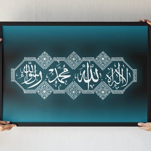 Puede incluir: Una impresión artística enmarcada de caligrafía islámica. La obra presenta escritura árabe blanca sobre un fondo degradado turquesa y negro. El marco es negro. La obra de arte está sostenida por dos personas.