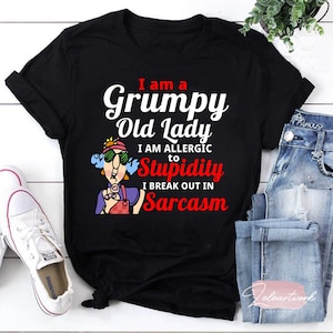 Könnte beinhalten: Schwarzes T-Shirt mit einer weißen Grafik einer Comic-Frau mit dem Text "I am a Grumpy Old Lady I am allergic to Stupidity I break out in Sarcasm".