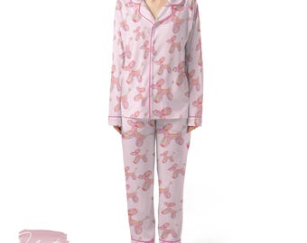 May include: Pale pink pyjama set with a repeating pattern of pink and yellow balloon dog illustrations. The long-sleeved top and trousers are trimmed with pink piping. The pyjamas have a button-down top with a notched collar.