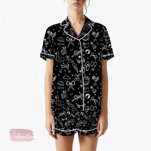 May include: Black pajama set with a white outline pattern of summer-themed icons, including bows, ice cream cones, and flamingos. The short-sleeved top and shorts have white trim.