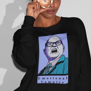 May include: Black sweatshirt with a graphic print of a man with glasses yelling. The text "Emotional Vampire" is printed below the graphic.