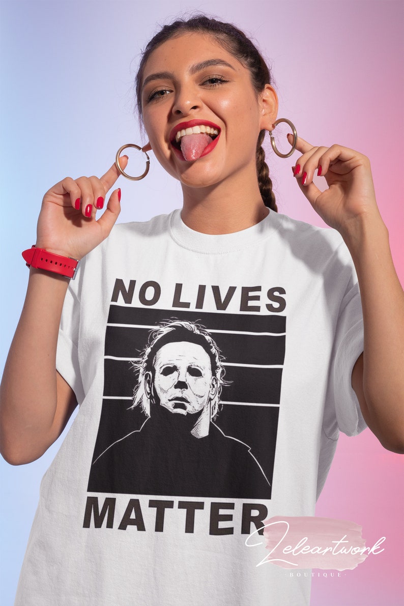 Puede incluir: Camiseta blanca con un gr&aacute;fico en blanco y negro de Michael Myers de la pel&iacute;cula Halloween. El texto "NO LIVES MATTER" est&aacute; impreso sobre el gr&aacute;fico.