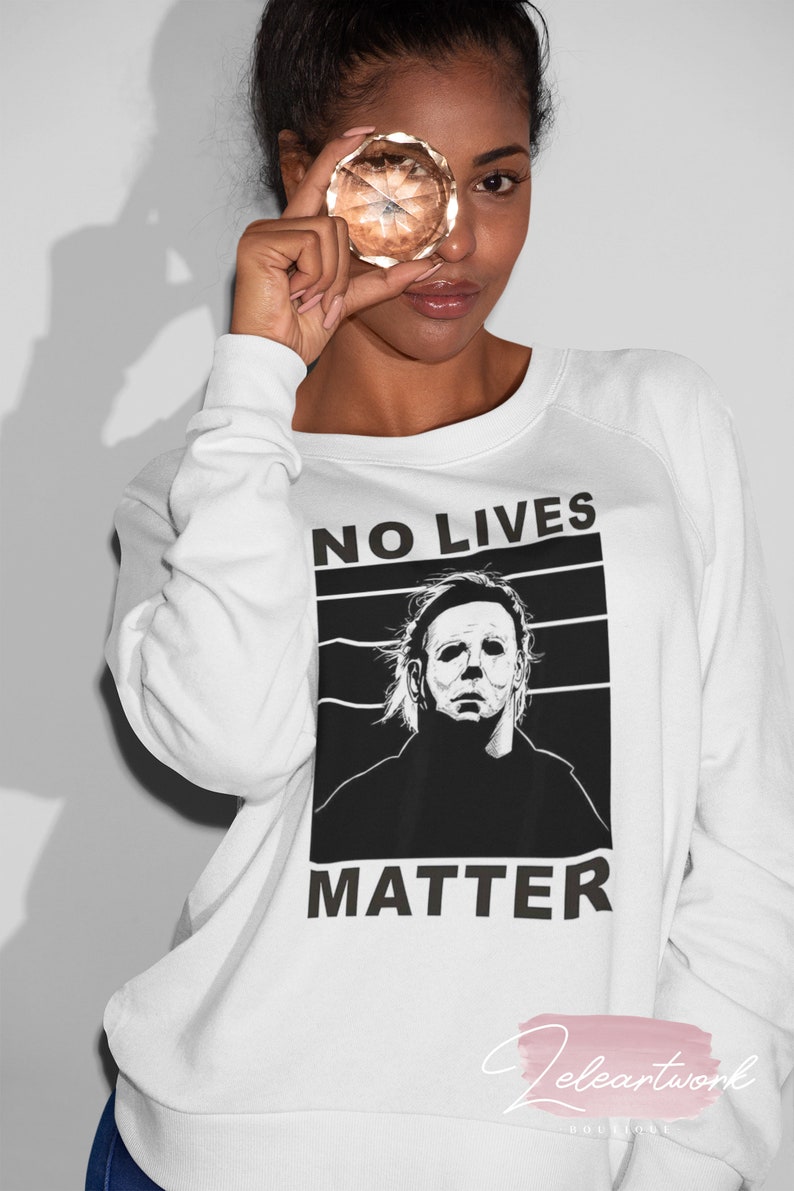 Puede incluir: Sudadera blanca con un estampado gr&aacute;fico en blanco y negro de un personaje de pel&iacute;cula de terror con el texto "NO LIVES MATTER".