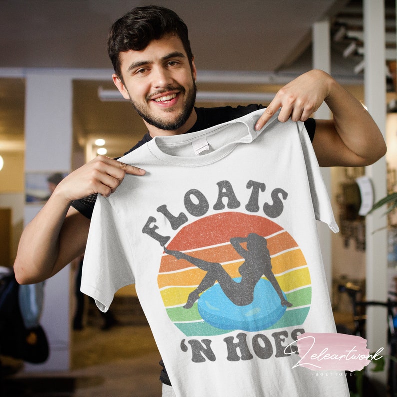 May include: White t-shirt with a retro-style graphic of a woman sitting on a float with the text "Floats 'N Hoes" in a vintage font.