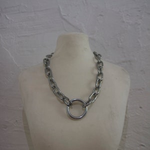 Może przedstawiać: Srebrny naszyjnik z łańcuszkiem i dużym srebrnym wisiorem w kształcie pierścienia.