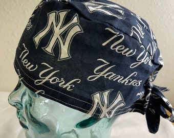 May include: A navy blue bandana featuring the New York Yankees logo and script. The white logo and script are printed across the fabric. The bandana is tied at the back.