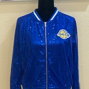 May include: A blue sequined bomber jacket with white stripes and a yellow and blue "Dubs City" patch with a basketball graphic.