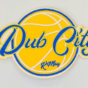 Könnte beinhalten: Eine weiße Keramik-Tasse mit schwarzem Henkel und dem Text "But First, Coffee" in fetter, schwarzer Schrift. Die Tasse steht vor einem verschwommenen Hintergrund, der eine gemütliche Umgebung andeutet.