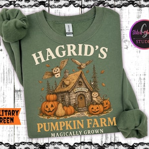 May include: Military green sweatshirt with a graphic of Hagrid's Pumpkin Farm. The design includes a cottage, pumpkins, owls, and the text "Hagrid's Pumpkin Farm Magically Grown".