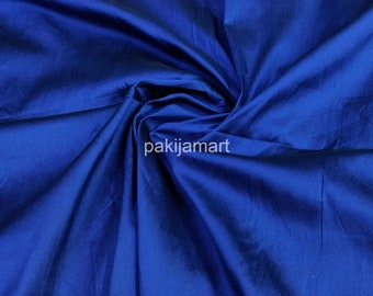 May include: A close-up of a deep blue fabric with a smooth, silky texture. The fabric is folded and draped, showcasing its luxurious feel.