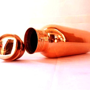 May include: A copper water bottle with a lid. The bottle is shiny and has a rounded shape.