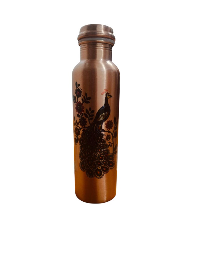 May include: A cylindrical copper water bottle featuring a dark brown printed graphic of a peacock perched on a flowering branch. The bottle has a smooth metallic finish, a narrow neck, and a matching copper cap with a visible white seal ring.