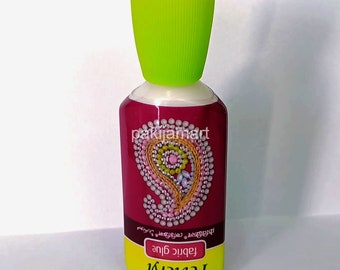 Puede incluir: Una botella amarilla de pegamento para tela Fevicryl con una tapa verde. La botella tiene un diseño paisley rosa y blanco con el texto "Pegamento para tela" y "Resistente al lavado" en negro.