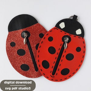 Pode incluir: Duas bolsas de zíper em forma de joaninha vermelha com manchas pretas e acabamento preto. Uma bolsa tem um acabamento vermelho brilhante. Ambas as bolsas têm zíperes prateados.