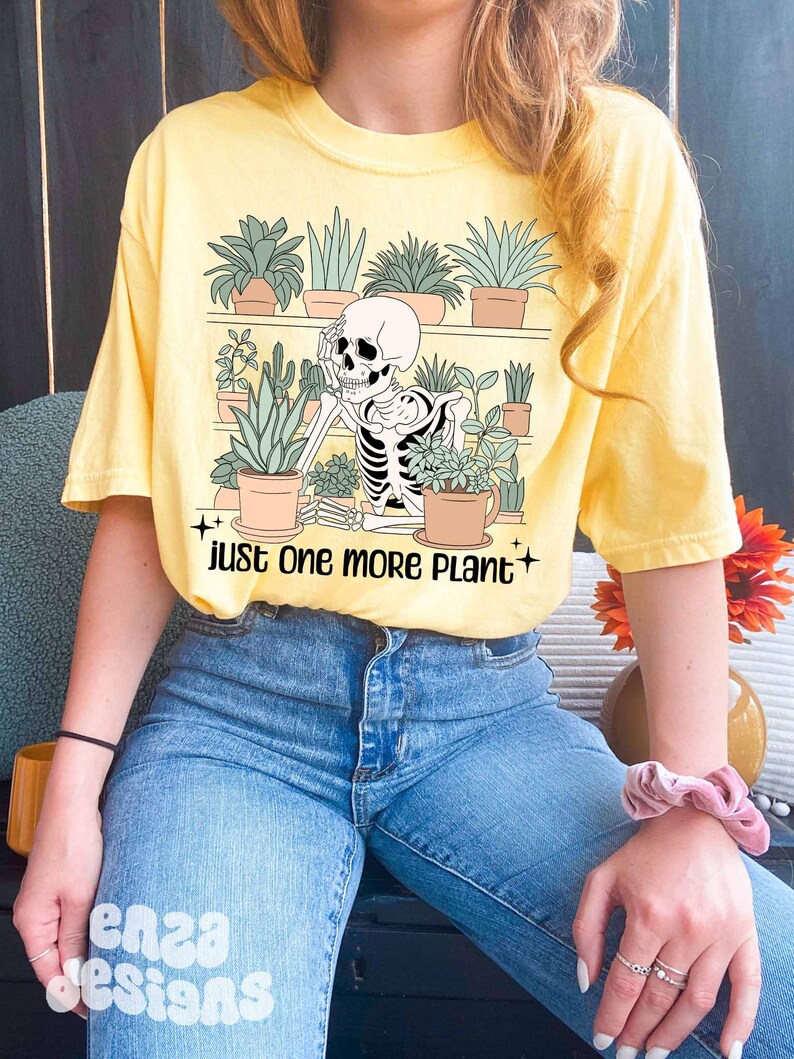 May include: A yellow t-shirt with a skeleton surrounded by potted plants. The text on the shirt reads "Just one more plant".