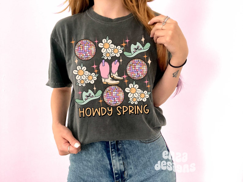 May include: Dark gray t-shirt with a graphic design featuring a disco ball, cowboy boots, daisies, and cowboy hats. The text "HOWDY SPRING" is printed in a retro font. The shirt is a relaxed fit.