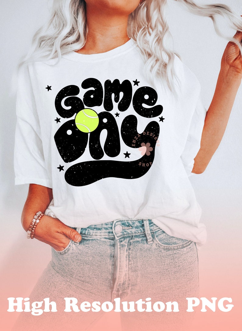 K&ouml;nnte beinhalten: Wei&szlig;es T-Shirt mit schwarzem Text, der "Game Day" sagt, mit einem gelben Tennisball in der Mitte des Textes. Der Text hat einen abgenutzten Look.
