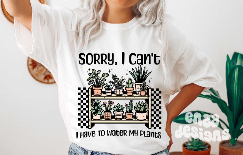 Puede incluir: Camiseta blanca con el texto "Lo siento, no puedo, tengo que regar mis plantas". El texto est&aacute; en negro y hay un gr&aacute;fico de un estante con plantas en macetas.