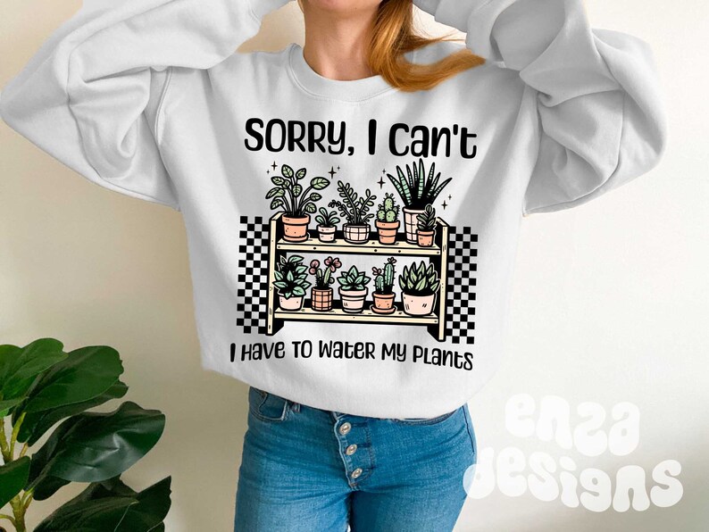 Puede incluir: Sudadera blanca con el texto "Lo siento, no puedo, tengo que regar mis plantas" y un gr&aacute;fico de una estanter&iacute;a con plantas en macetas.