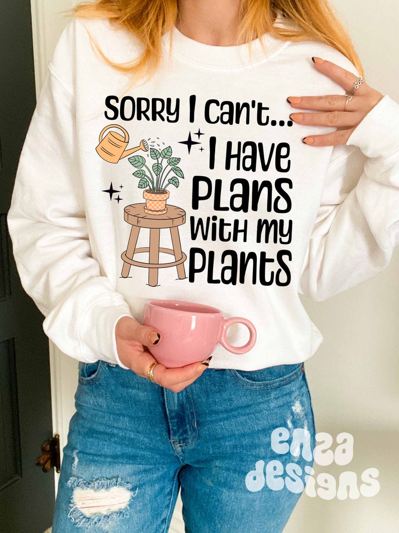 May include: White sweatshirt with the text "Sorry I can't... I have plans with my plants" and a cartoon illustration of a potted plant on a stool with a watering can.