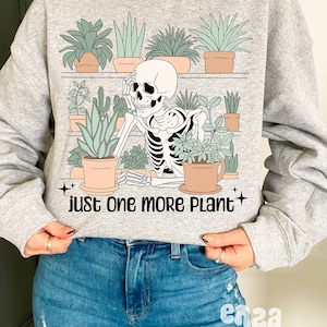 May include: A gray sweatshirt with a skeleton surrounded by potted plants. The text "just one more plant" is printed below the skeleton.
