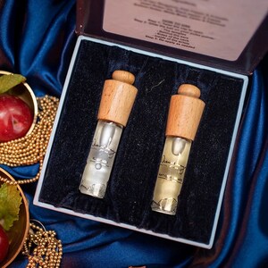 May include: Two small glass bottles with wooden caps and gold labels. The bottles are in a white box with a black velvet lining. The labels read "Darjeeling" and "Reflection" and "Antique White".