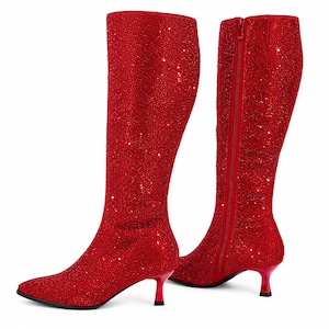 May include: A pair of knee-high boots covered in small red rhinestones. The boots feature a pointed toe, a slim kitten heel, and a full-length vertical zipper on the inner side. The exterior surface is entirely textured with sparkling red crystals.