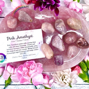 May include: Pink Amethyst tumbled stones on a pink rose quartz dish. The stones are a light pink colour with white and grey streaks. The dish is a light pink colour with a smooth surface. The stones are surrounded by pink flowers.