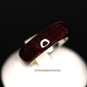 May include: A red glitter ring with a shiny finish. The ring is on a white surface.