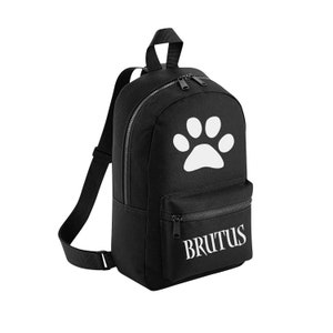 May include: Black canvas backpack with a white paw print and the name "BRUTUS" printed on the front.
