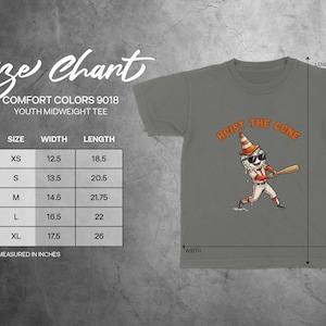 Może przedstawiać: Szara koszulka dla młodzieży z napisem "HOIST THE CONE" i grafiką baseballową. Tabela rozmiar&oacute;w pokazuje wymiary w cm: XS (31,75 cm szerokości, 47 cm długości), S (34,3 cm szerokości, 52,1 cm długości), M (36,8 cm szerokości, 55,2 cm długości), L (41,9 cm szerokości, 55,9 cm długości) i XL (44,5 cm szerokości, 66 cm długości).