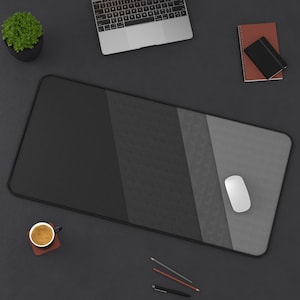 May include: A black, gray, and white striped desk mat with a white computer mouse on the right side. A laptop computer, a cup of coffee, pencils, and a pen are also on the desk.