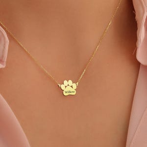 May include: Gold paw print necklace with the name "Willow" engraved on it.