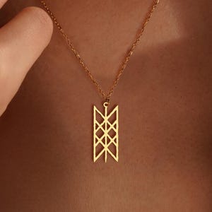 May include: A gold pendant necklace with a geometric design. The pendant is rectangular with intersecting lines and shapes. The necklace is worn around the neck. The pendant's design is approximately 2.5 cm in length.