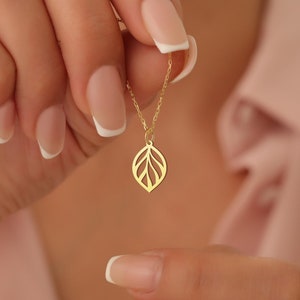 May include: A gold necklace with a delicate leaf pendant. The pendant is made of a thin, openwork design and has a subtle shine.