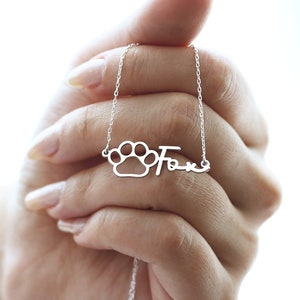 May include: Silver necklace with a paw print charm and the name "Fox" written in cursive.