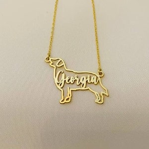 May include: Gold necklace with a dog silhouette pendant. The dog's name, "Georgia", is written inside the silhouette.