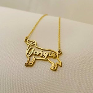 May include: Gold necklace with a dog silhouette pendant. The dog's name, "Georgia", is cut out of the pendant.