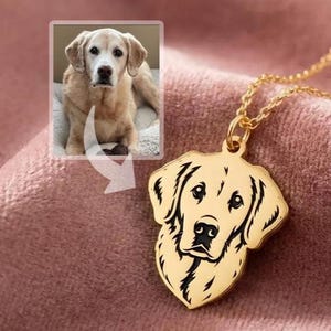 May include: A gold-colored pendant necklace featuring a dog's head silhouette. The pendant is a detailed outline of a dog's face. The necklace is on a pink surface, with a small image of a dog in the upper left corner.