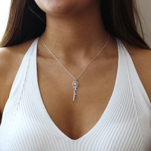 May include: A silver necklace with a delicate flower charm and the name "Katherine" spelled out vertically below it.