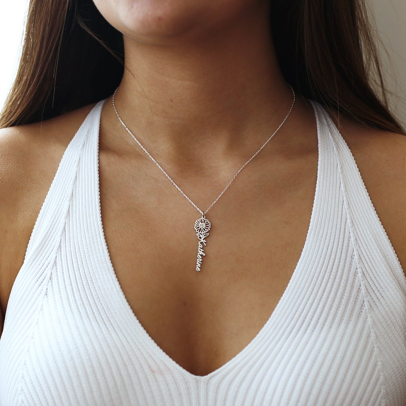 May include: A silver necklace with a delicate flower charm and the name "Katherine" spelled out vertically below it.