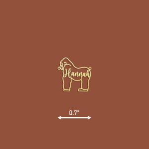 May include: Gold-colored wooden cutout of a gorilla with the name "Hannah" written inside. The cutout is 0.7 inches tall.